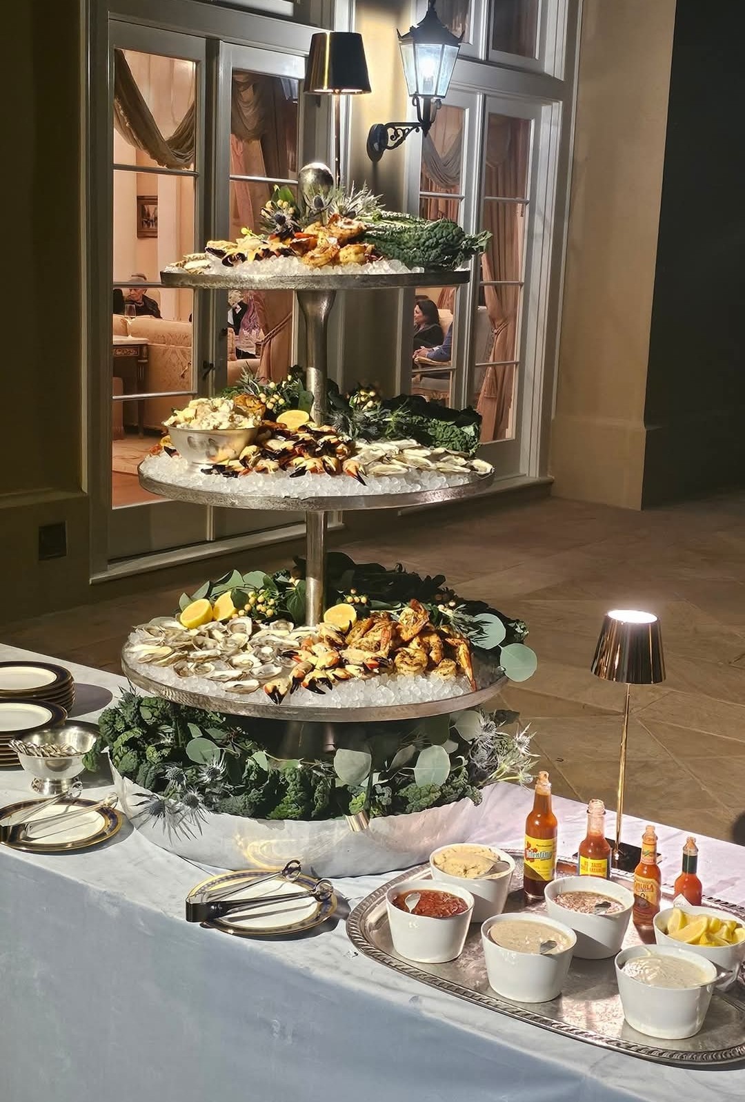 A multi-tier seafood display on a table with sauces and garnishes.