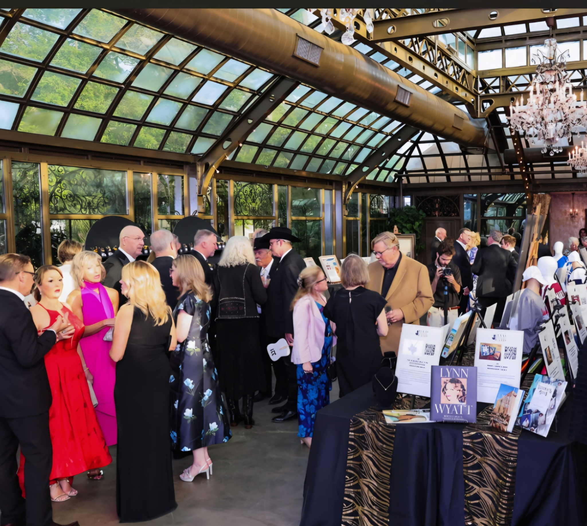 Group of people in formal attire attending an event in a glass-enclosed space.