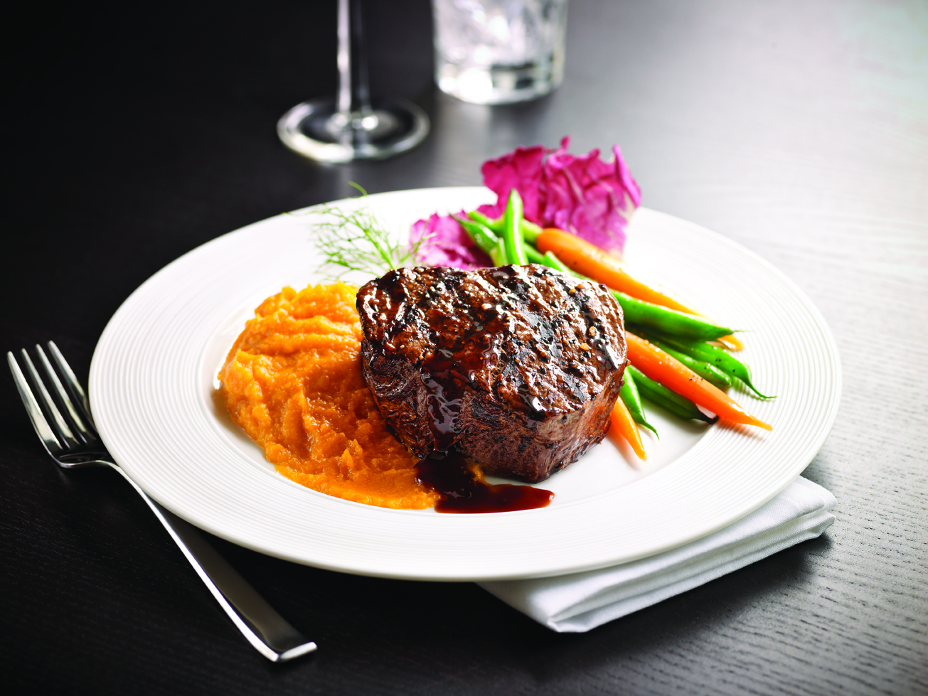 Plate of cooked steak with mashed sweet potatoes and mixed vegetables